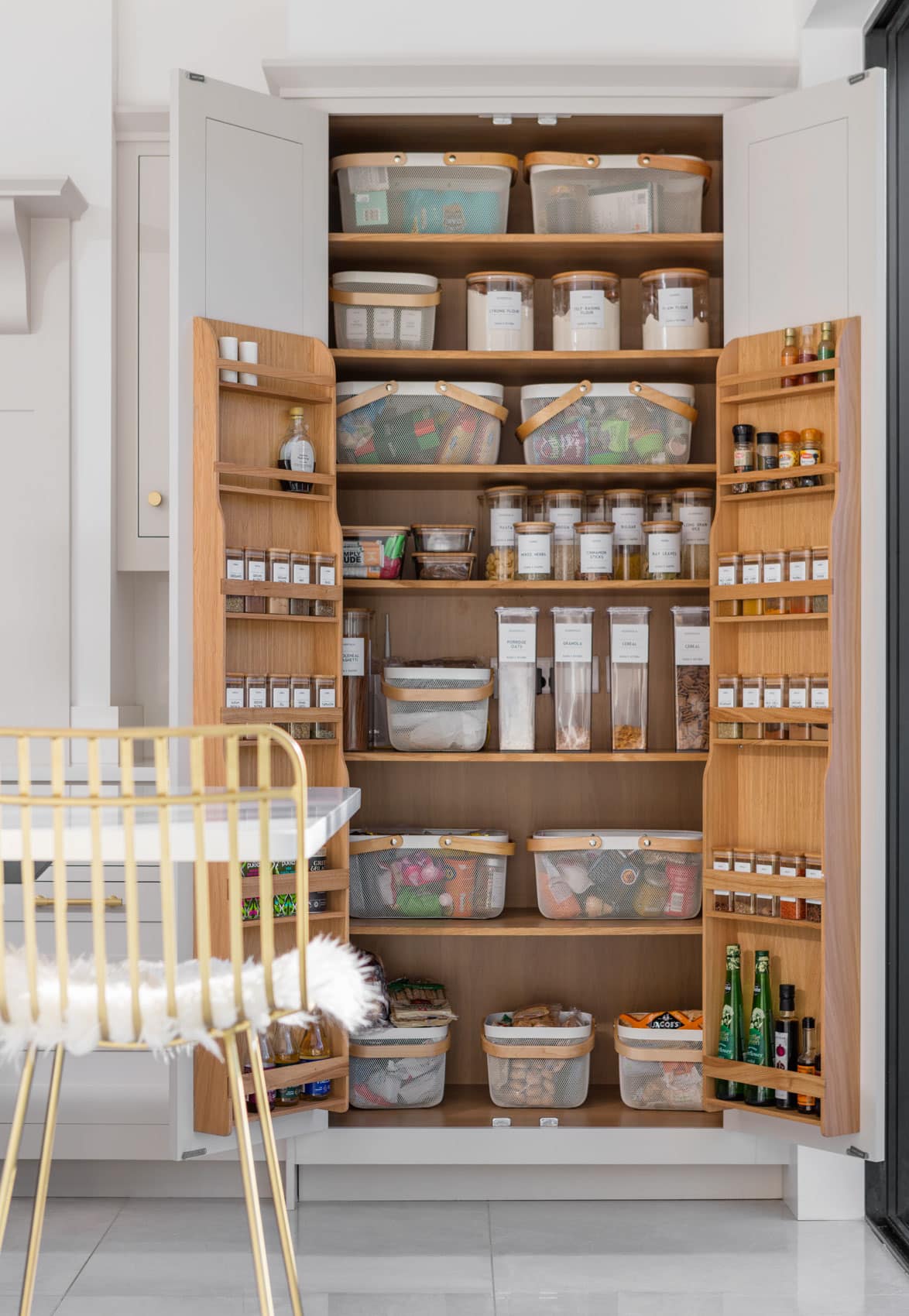 White Shaker kitchen pantry open to show oak interior and organised storage