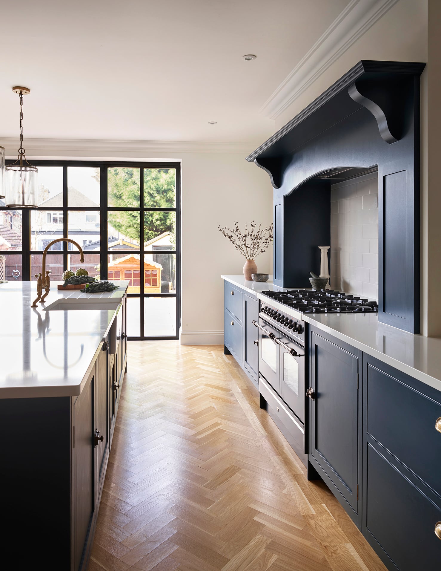Rich blue kitchen cabinetry and cooker alcove featuring white worktops