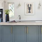 Blue kitchen island featuring Arbor cabinetry with gold handles and natural wood worktop