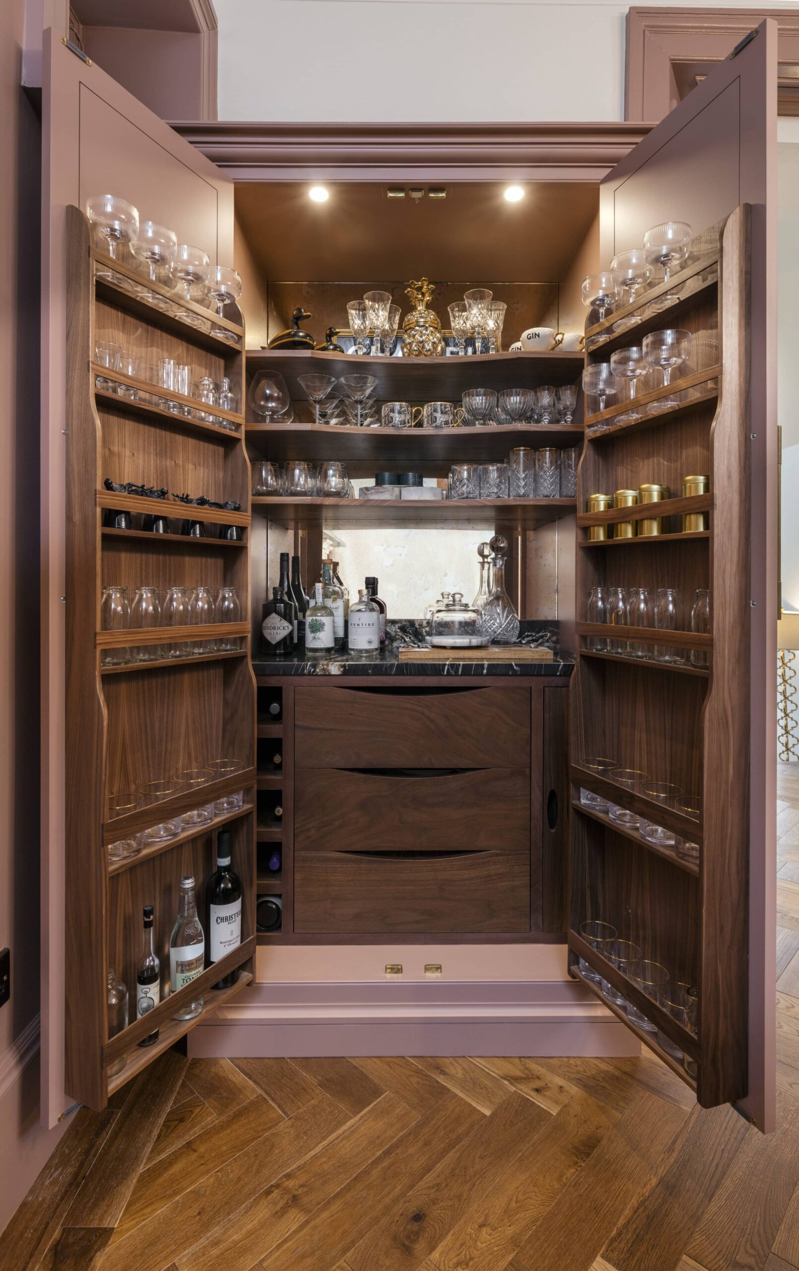Large pink Original design kitchen pantry open to reveal walnut interior with organised storage