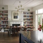 Blue kitchen island with black and brown marble worktop overlooking open plan dining area