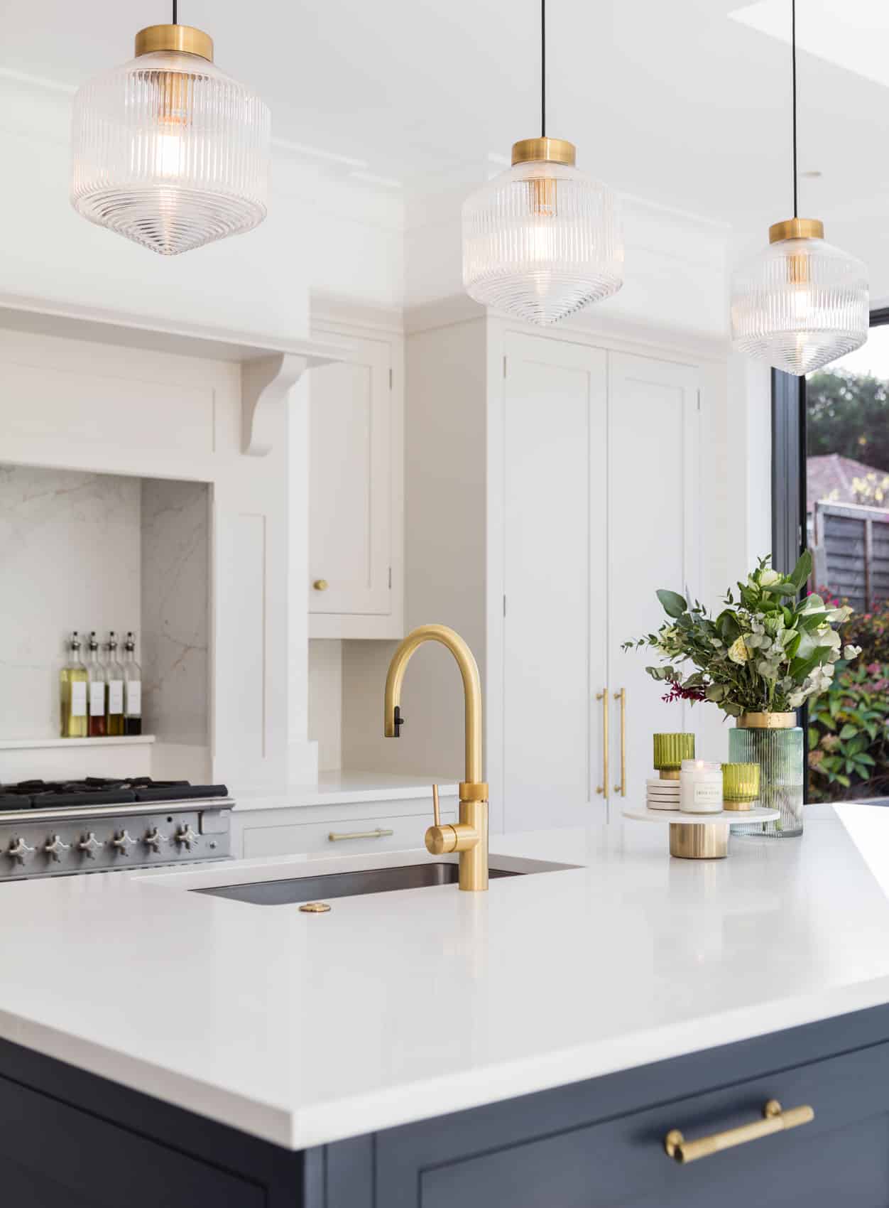 Blue Shaker kitchen island with gold handles, white worktop and integrated sink with gold tap