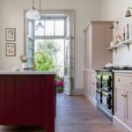 Arbor kitchen design with blush pink cabinetry and burgundy kitchen island featuring a white worktop