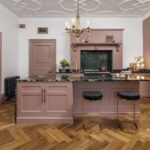 Pink Original kitchen cabinetry with black worktops against pink walls