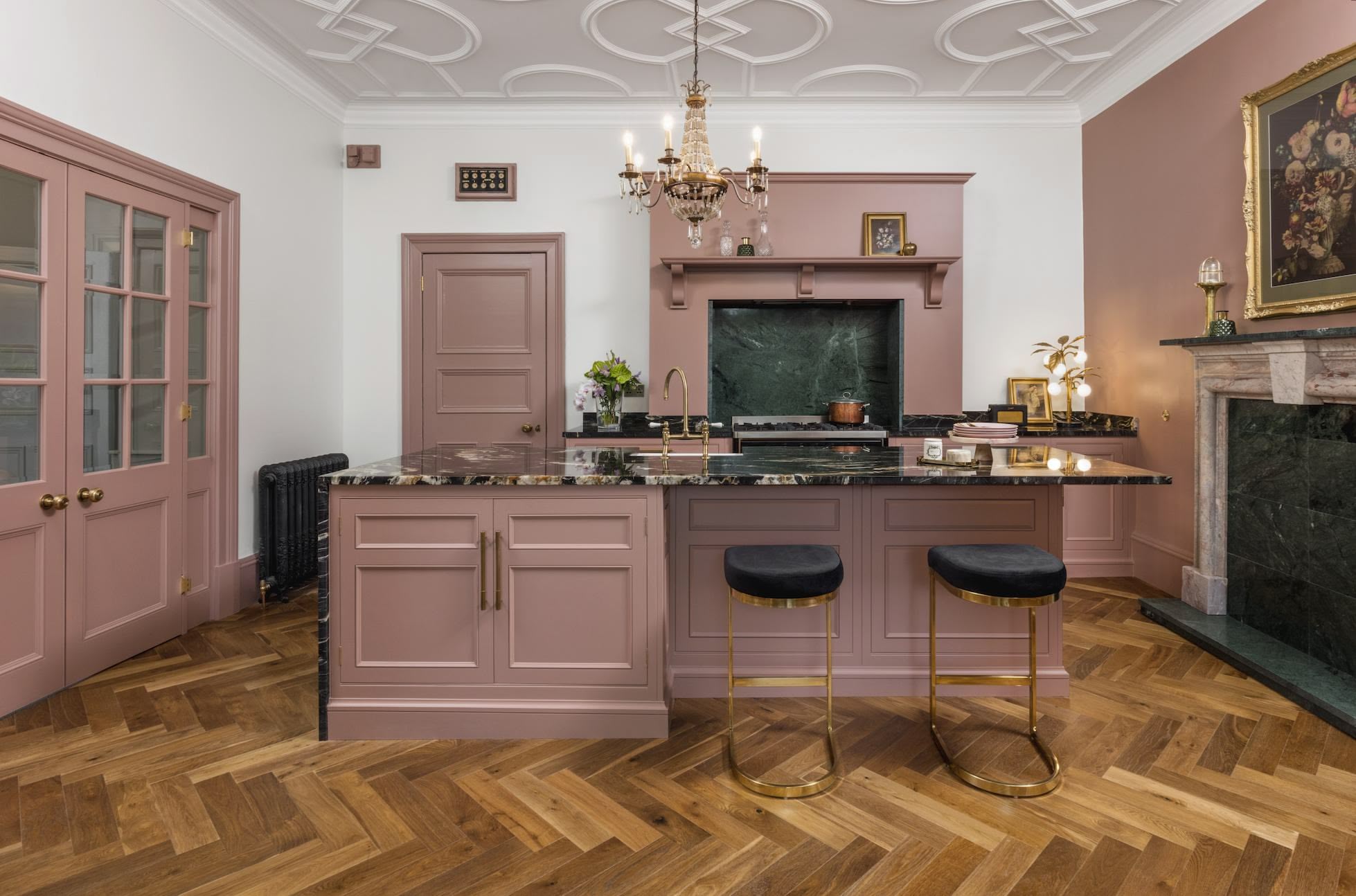 Pink Original kitchen cabinetry with black worktops against pink walls