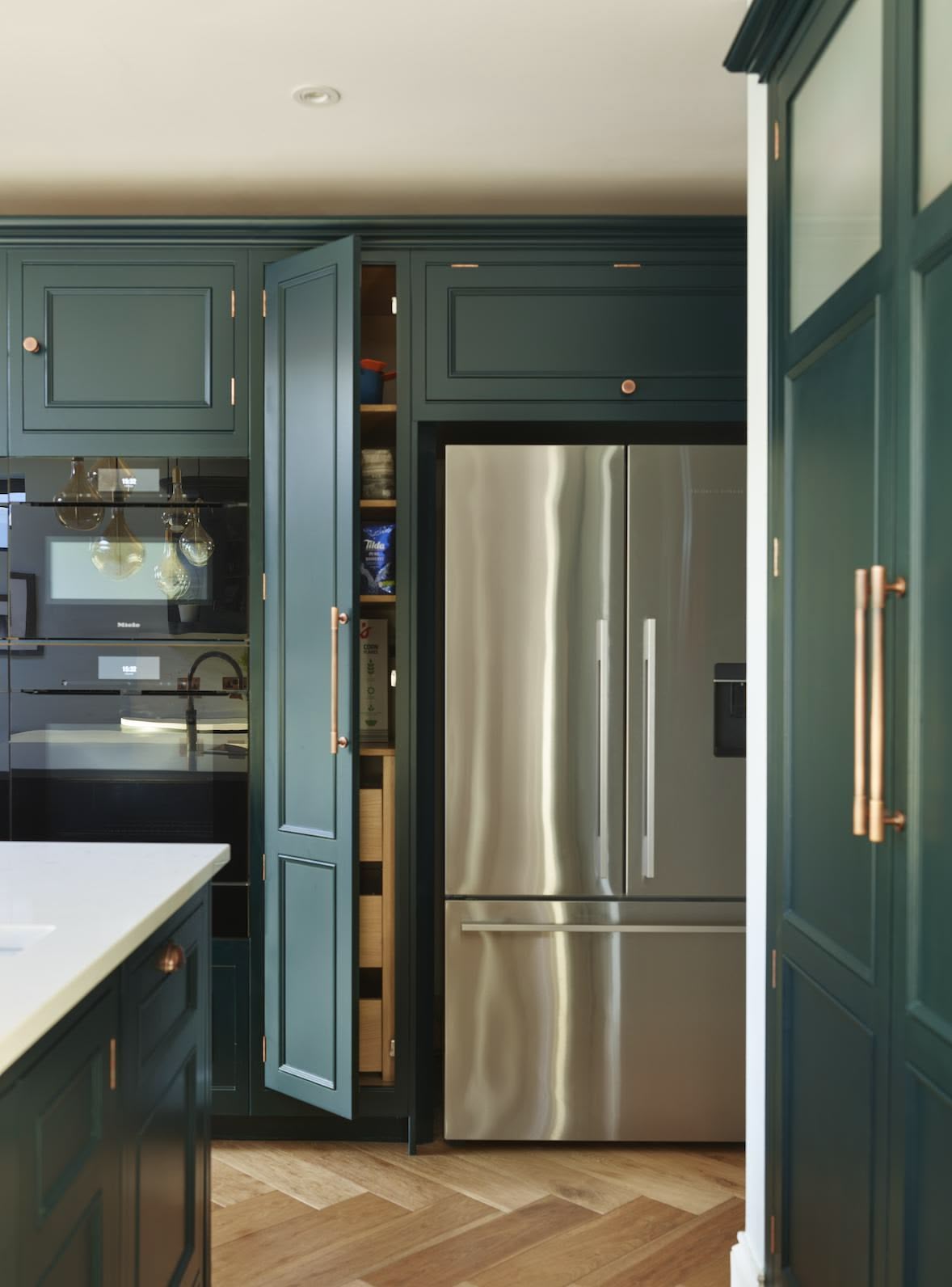 Vibrant green kitchen cabinetry with organised pantry and silver American style fridge