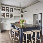 Blue kitchen island with black and brown marble worktop and natural wooden smile stools