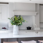 Deep grey Shaker kitchen island with white worktop and natural wood smile stools