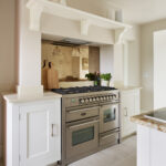 White kitchen cabinetry and cooker alcove with bronze mirrored splashback