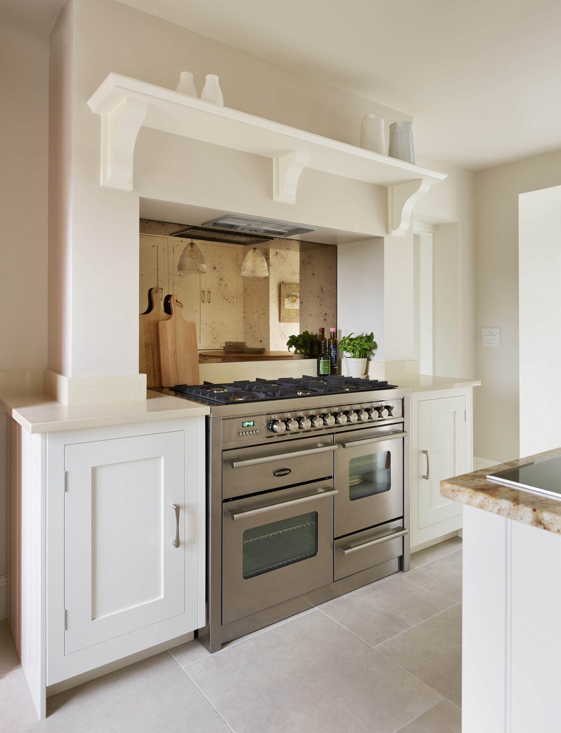 White kitchen cabinetry and cooker alcove with bronze mirrored splashback