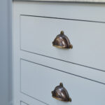 Closeup of pale blue Shaker drawers with antique brass handles