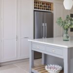 White kitchen cabinetry with wine rack above American style fridge
