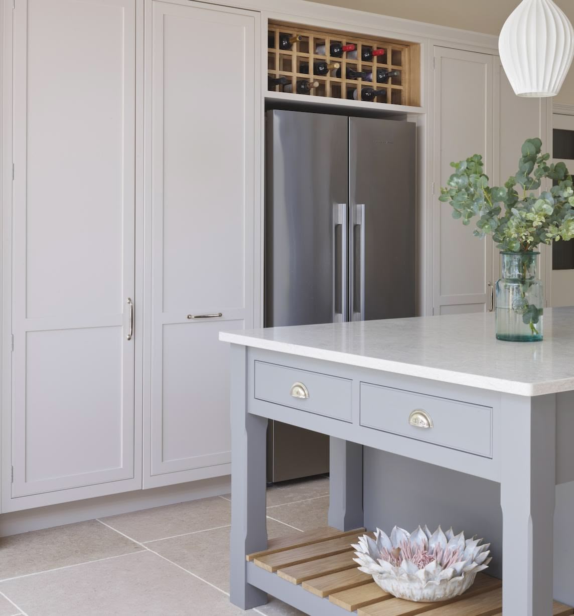 White kitchen cabinetry with wine rack above American style fridge