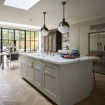 Soft grey kitchen island with white worktop and integrated sink with gold tap