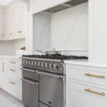 Cooker surrounded by white Shaker kitchen cabinetry with white marble splashback