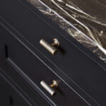Closeup of black Shaker kitchen drawers with brass handles