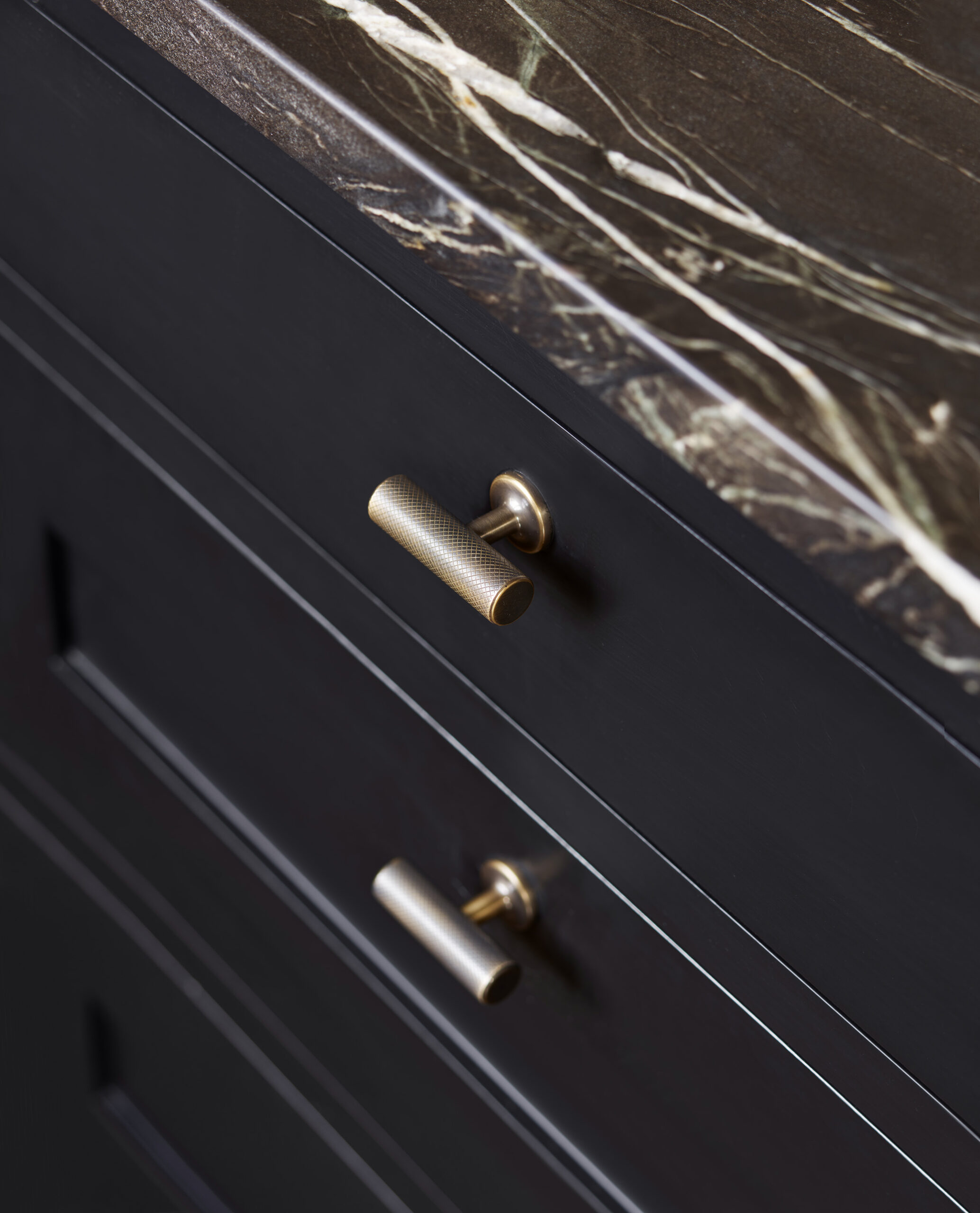 Closeup of black Shaker kitchen drawers with brass handles