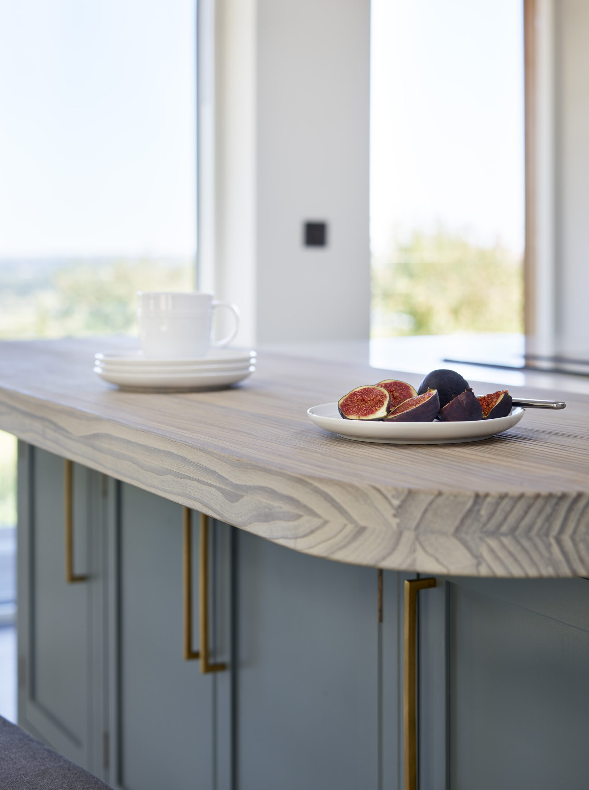 Closeup of a blue kitchen island featuring Arbor cabinetry with gold handles and a natural wood worktop