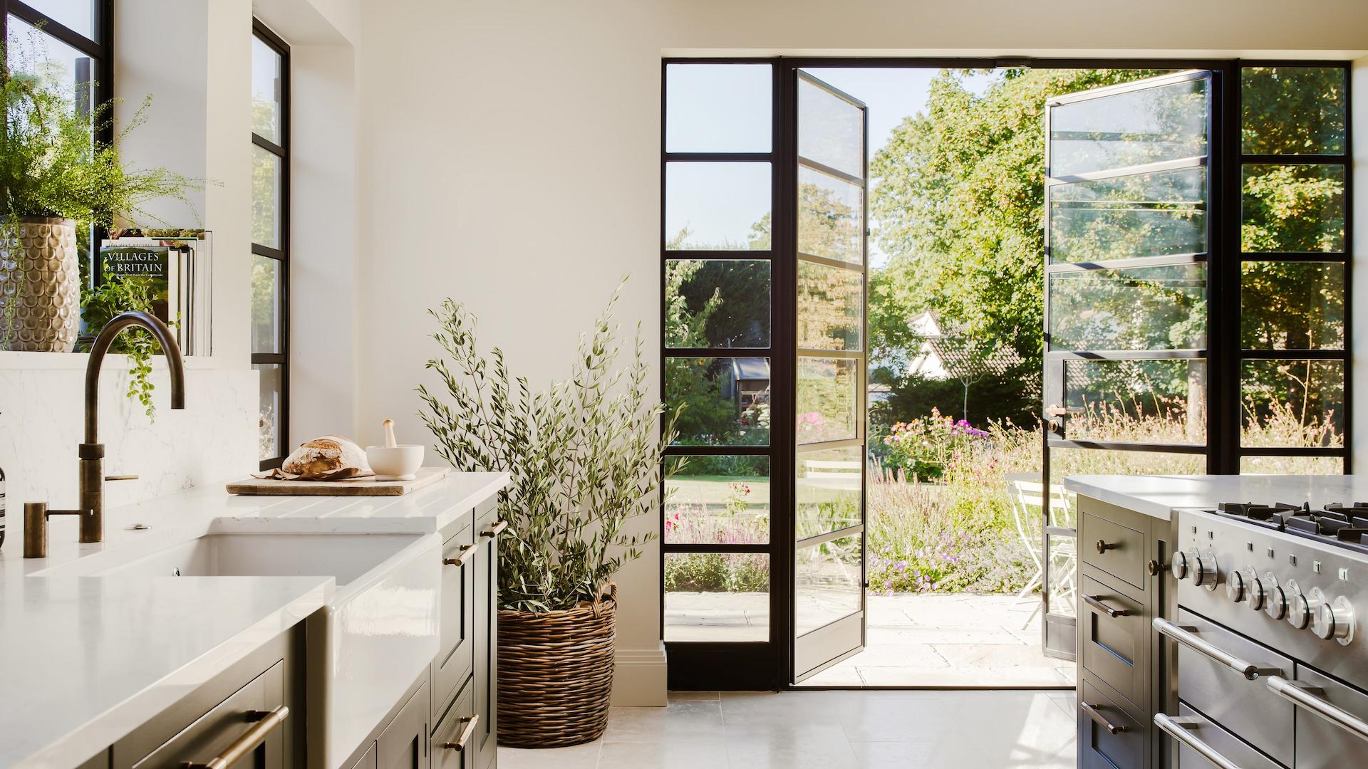 Deep green Shaker kitchen design with large glass door to the garden