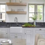 White Original kitchen cabinetry with black worktops and white sink with silver tap