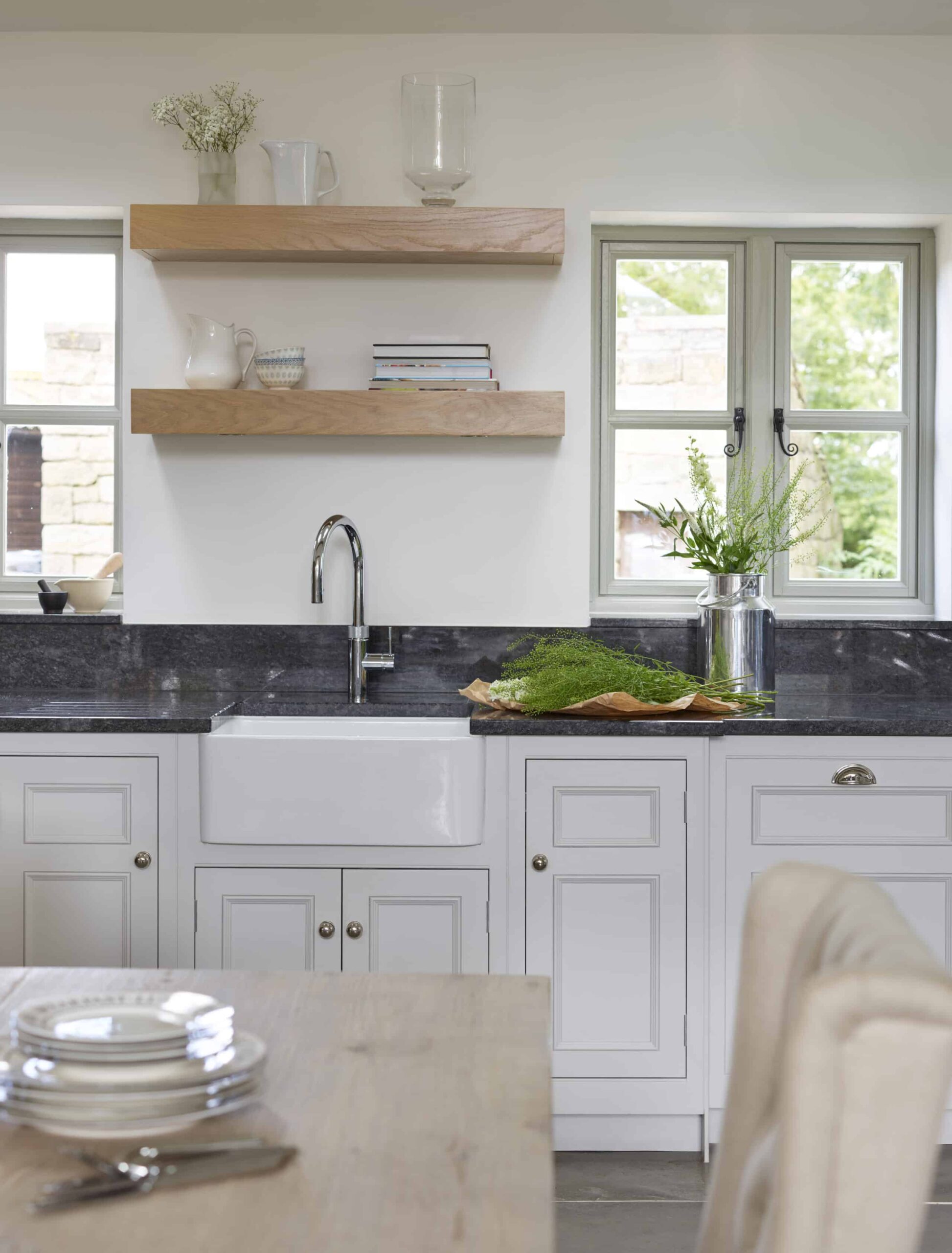 White Original kitchen cabinetry with black worktops and white sink with silver tap