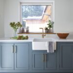 Blue utility room cabinetry with white worktop featuring white basin sink with gold tap