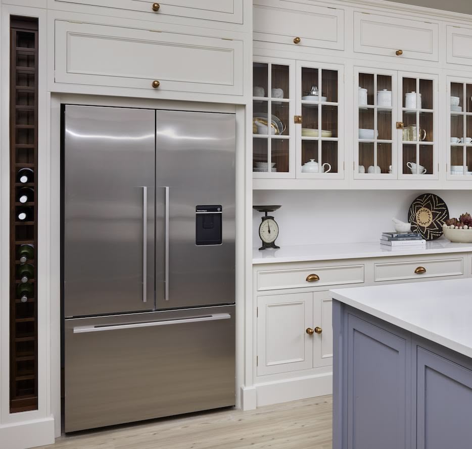 White kitchen cabinetry with wine rack alongside American style fridge
