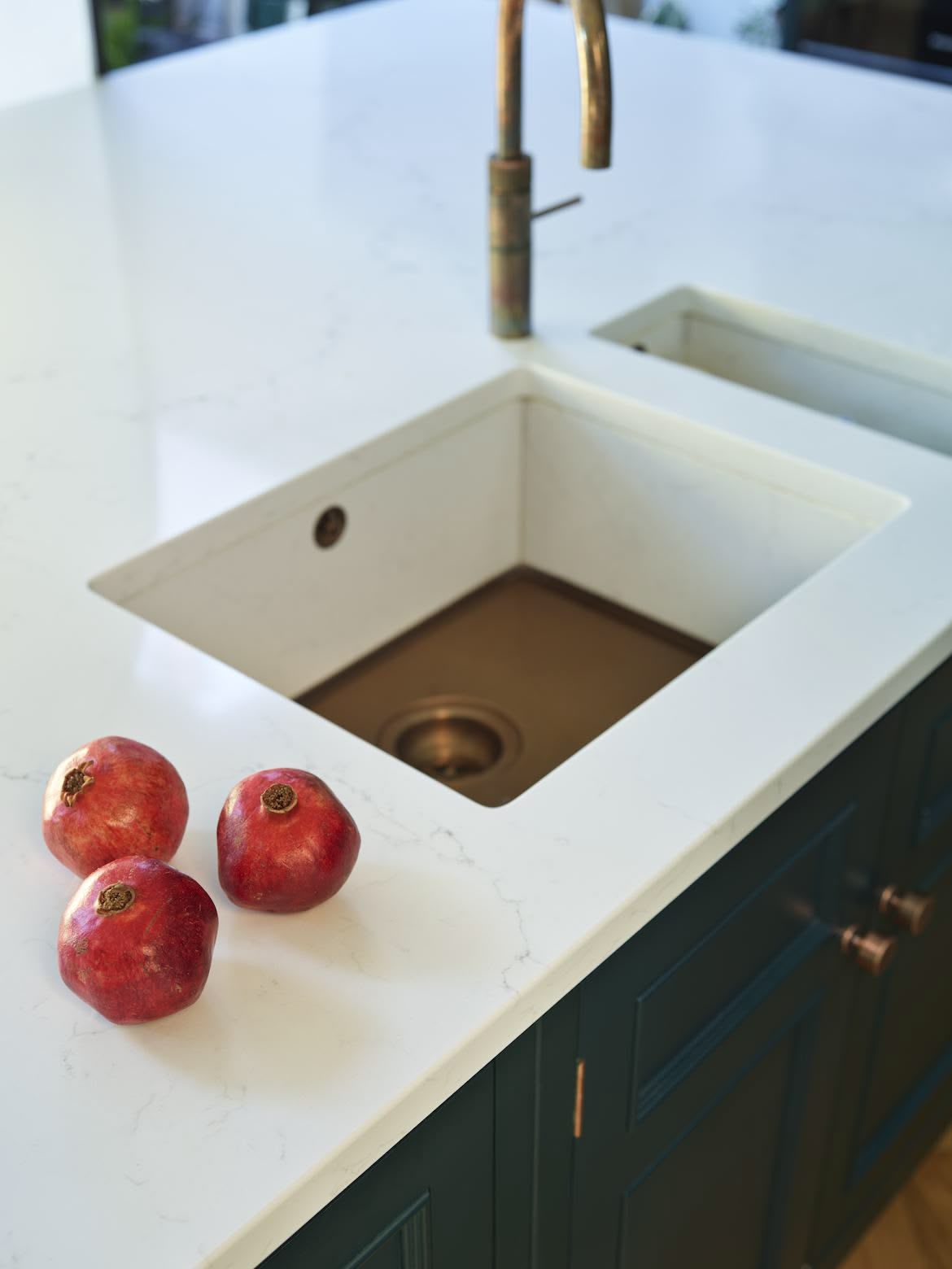 White kitchen island worktop with white sink featuring a brass base and tap
