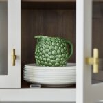 Closeup of white Linear kitchen cupboard open to show dark wood interior and organised shelving