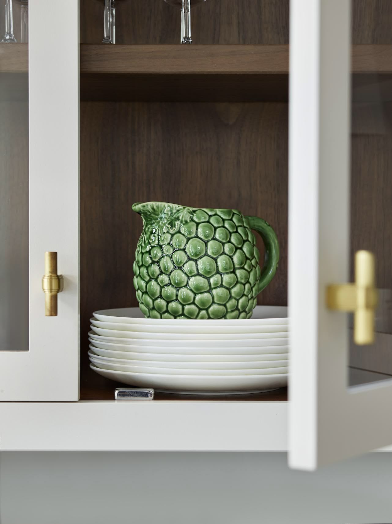 Closeup of white Linear kitchen cupboard open to show dark wood interior and organised shelving