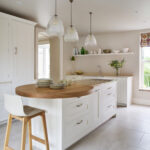 White Shaker kitchen island with round oak extension with white and walnut bar stools