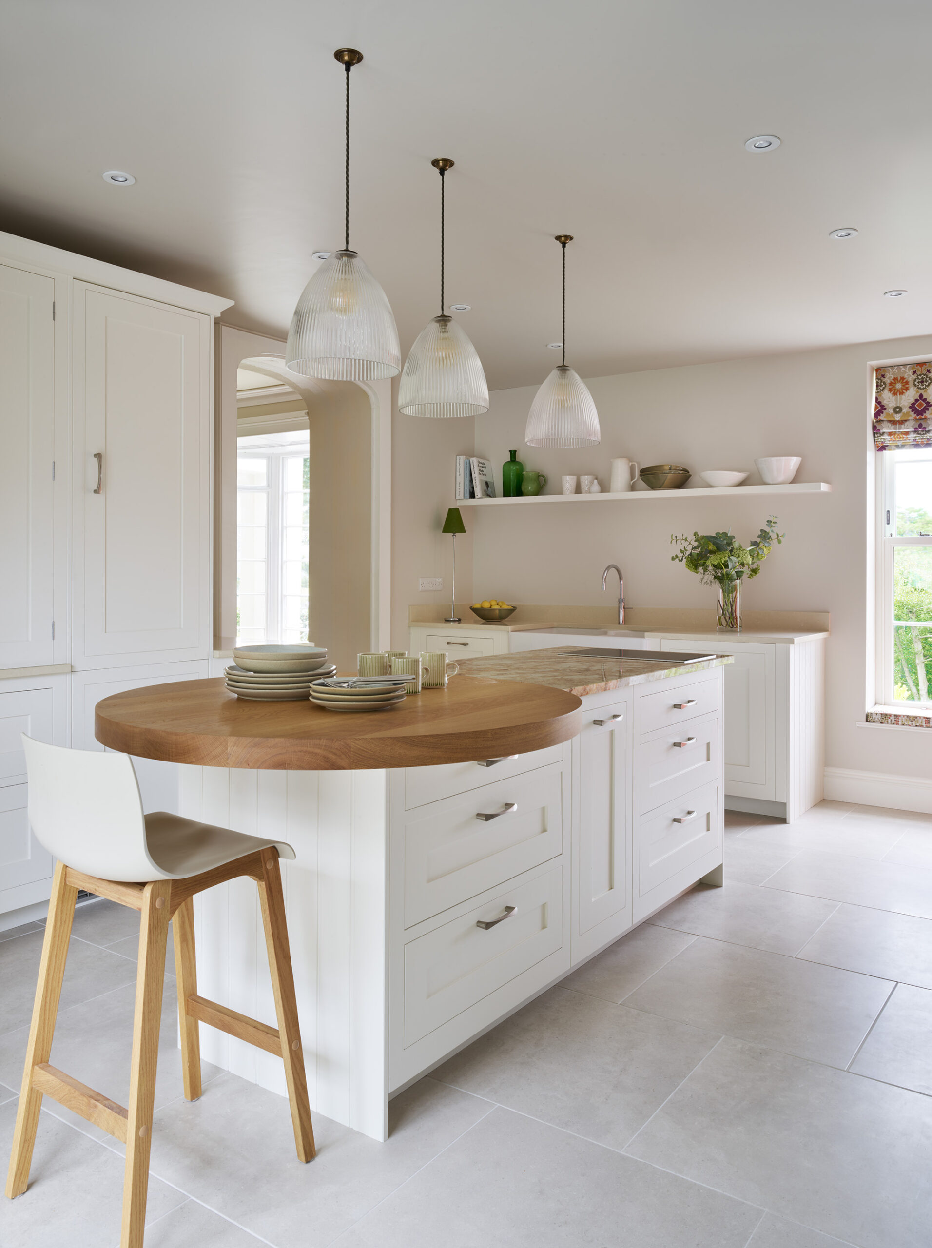 White Shaker kitchen island with round oak extension with white and walnut bar stools