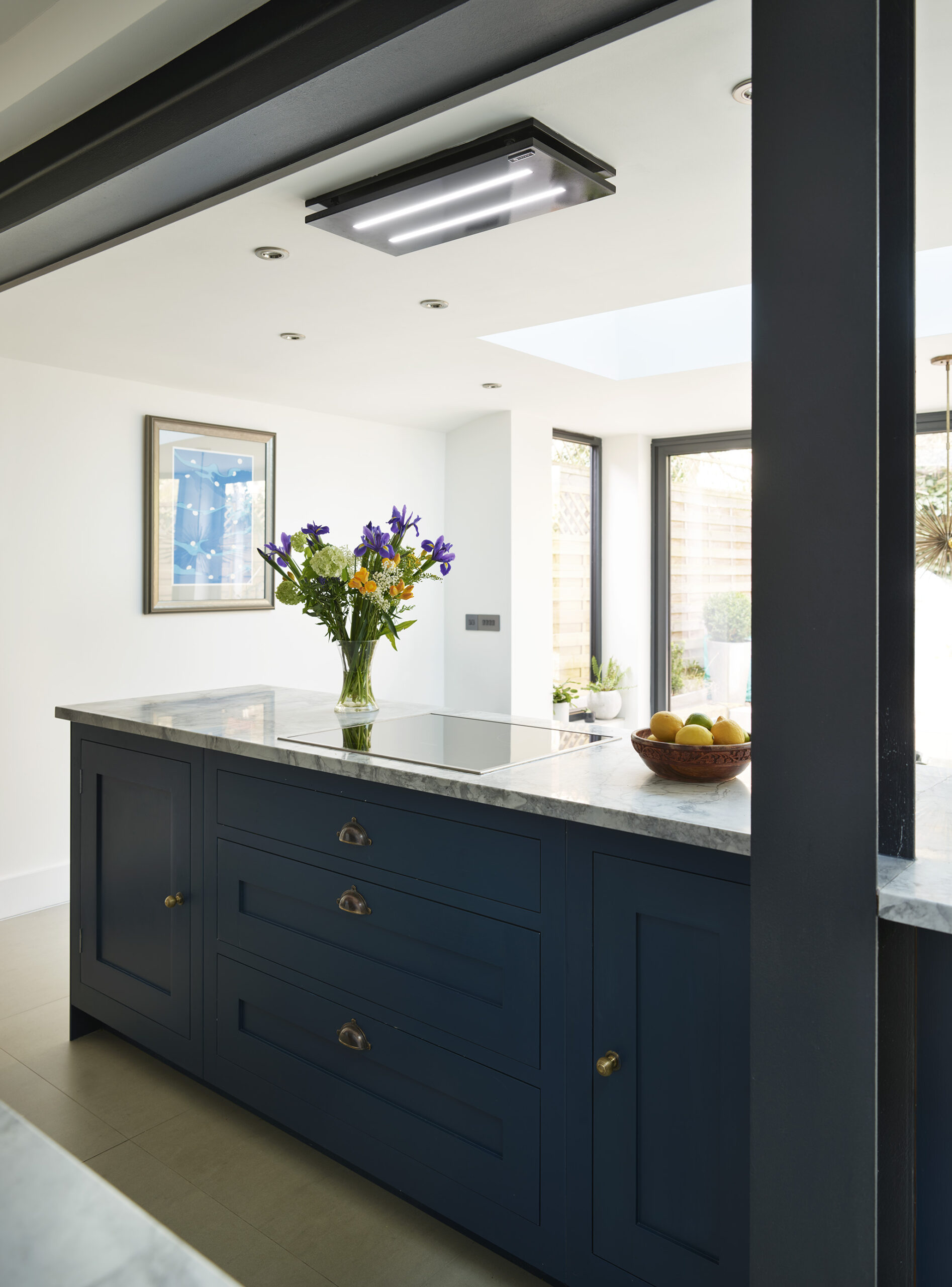 Blue Shaker kitchen island with white granite worktop seen through external window