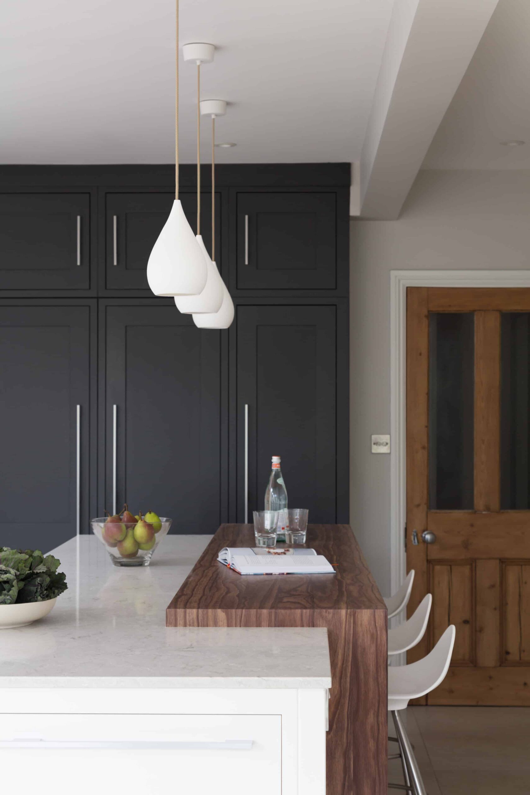 Dark kitchen pantry cabinetry against a white kitchen island with dark oak extension