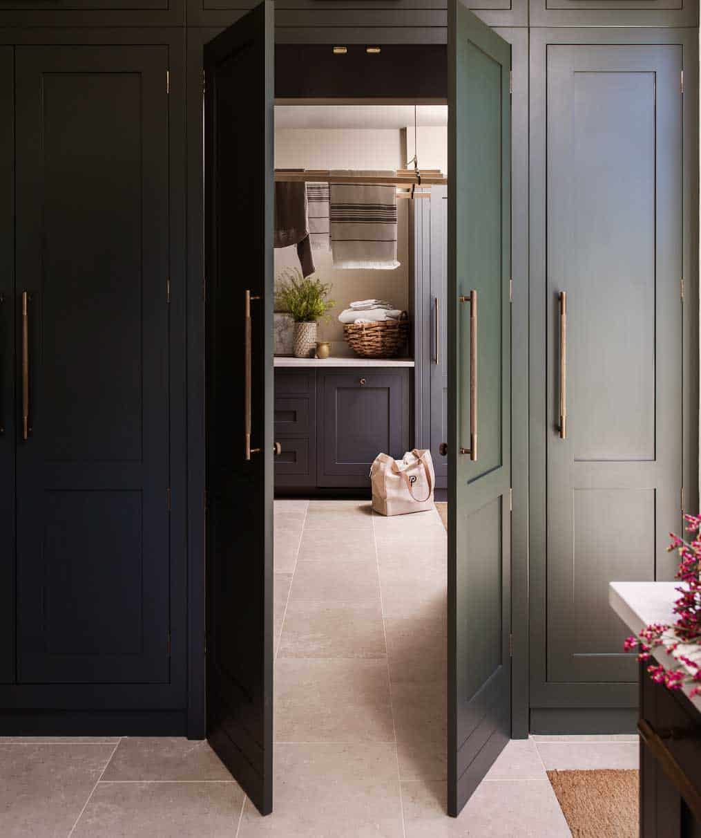 Dark green kitchen doors open to show hidden utility room