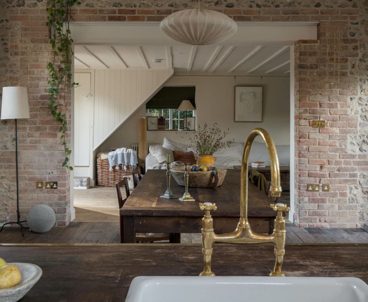 Dark wood kitchen island worktop with white sink and brass tap overlooking open plan dining area