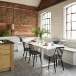 White Arbor kitchen cabinetry with an oak kitchen island with black worktop and dining area with banquette seating