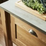Closeup of Shaker oak kitchen island drawer with silver handle and grey granite worktop