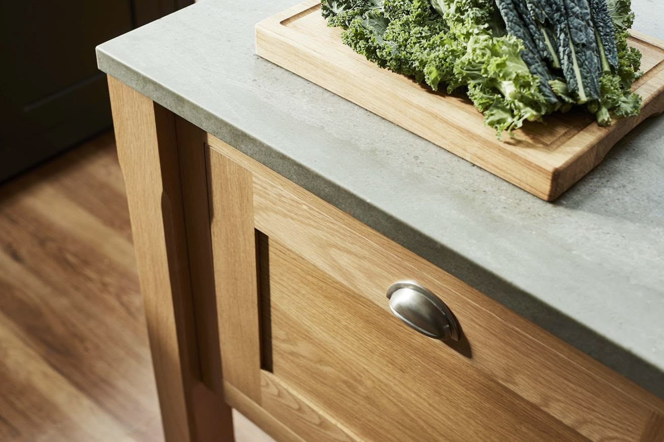 Closeup of Shaker oak kitchen island drawer with silver handle and grey granite worktop