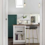 White kitchen island and bold green cabinetry seen from kitchen entrance