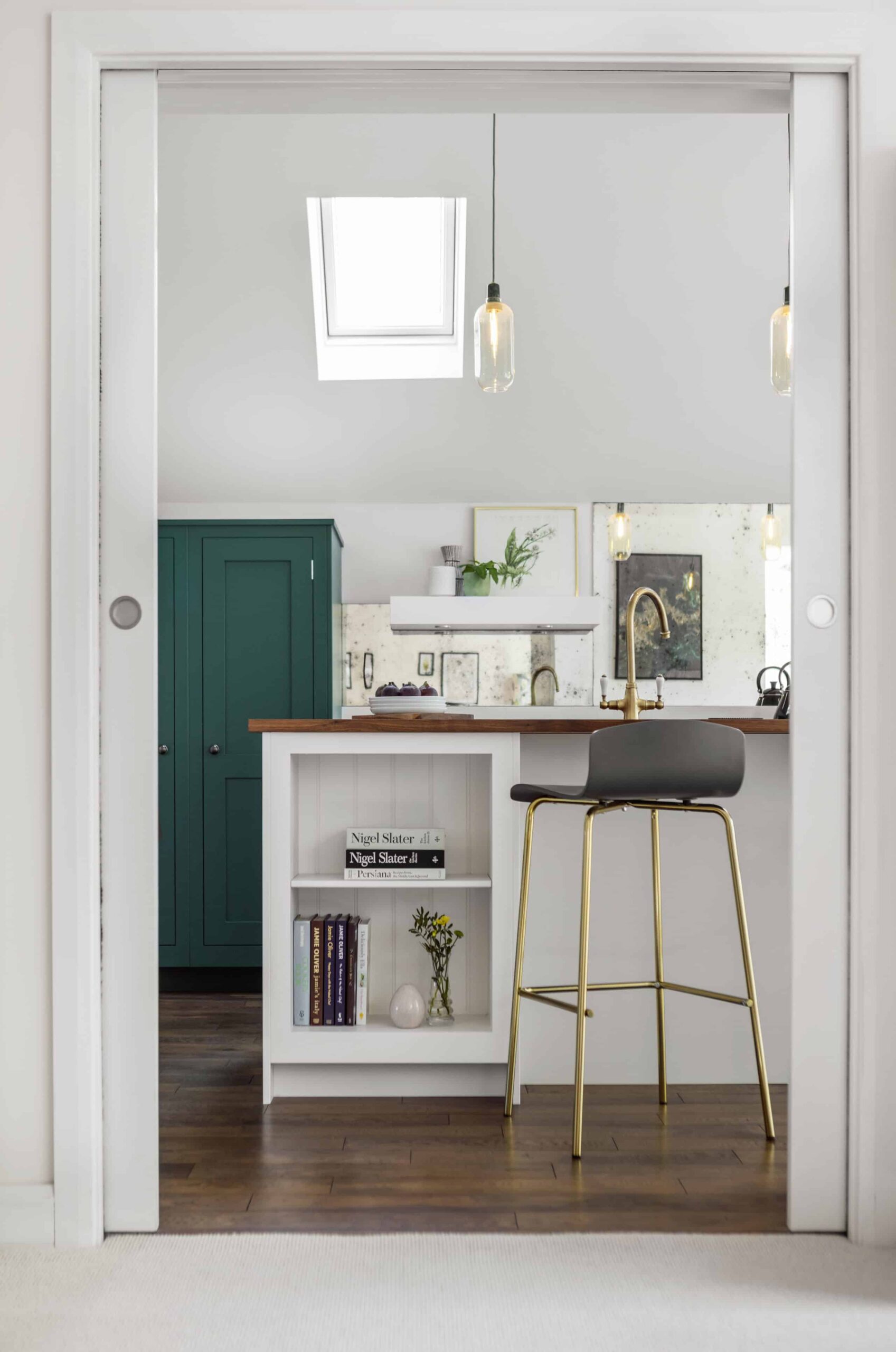 White kitchen island and bold green cabinetry seen from kitchen entrance