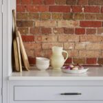 Light grey kitchen cabinetry with white worktop