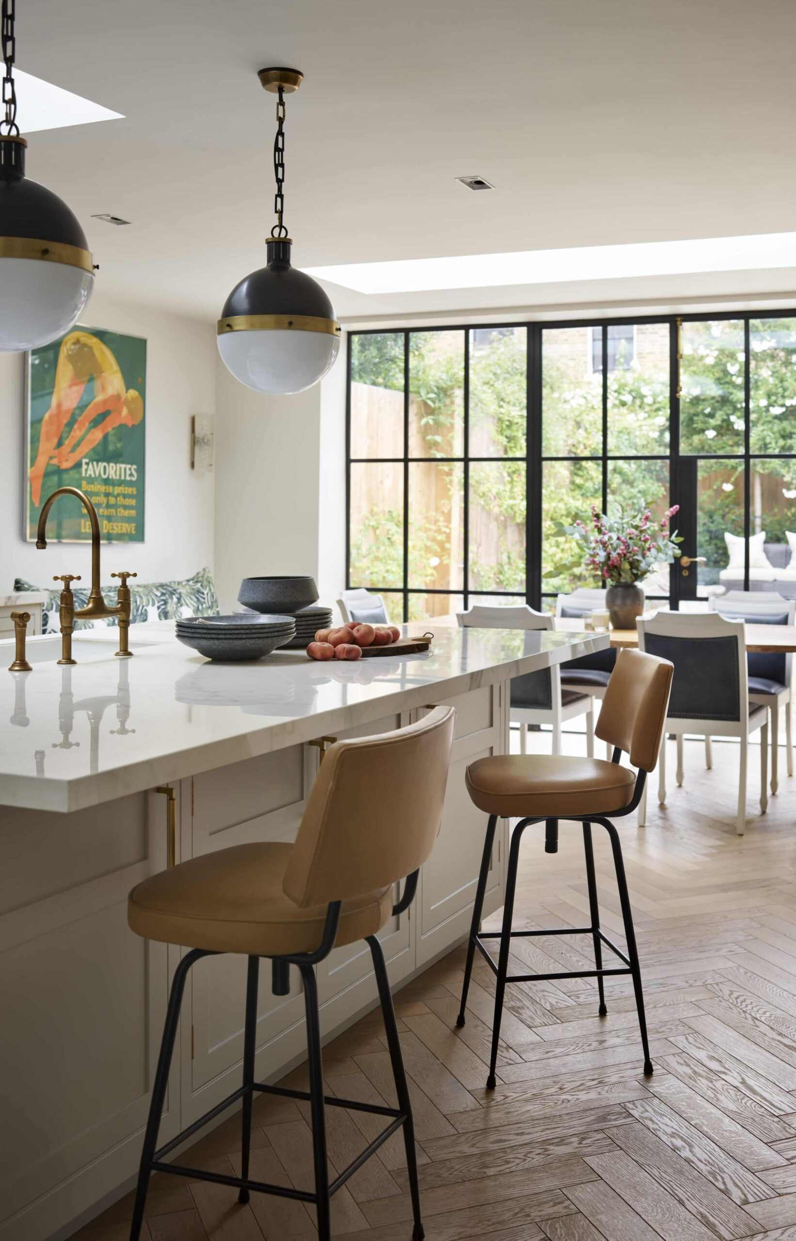 Beige kitchen island with white worktop and tan coloured bar stools overlooking open plan dining area
