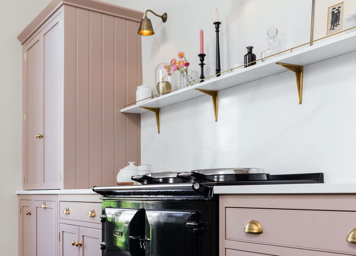 Pale pink kitchen cabinetry with white worktops