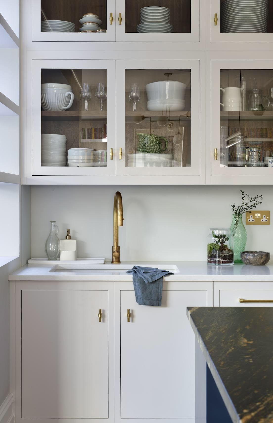 White kitchen cabinetry with glass doors showing organised storage