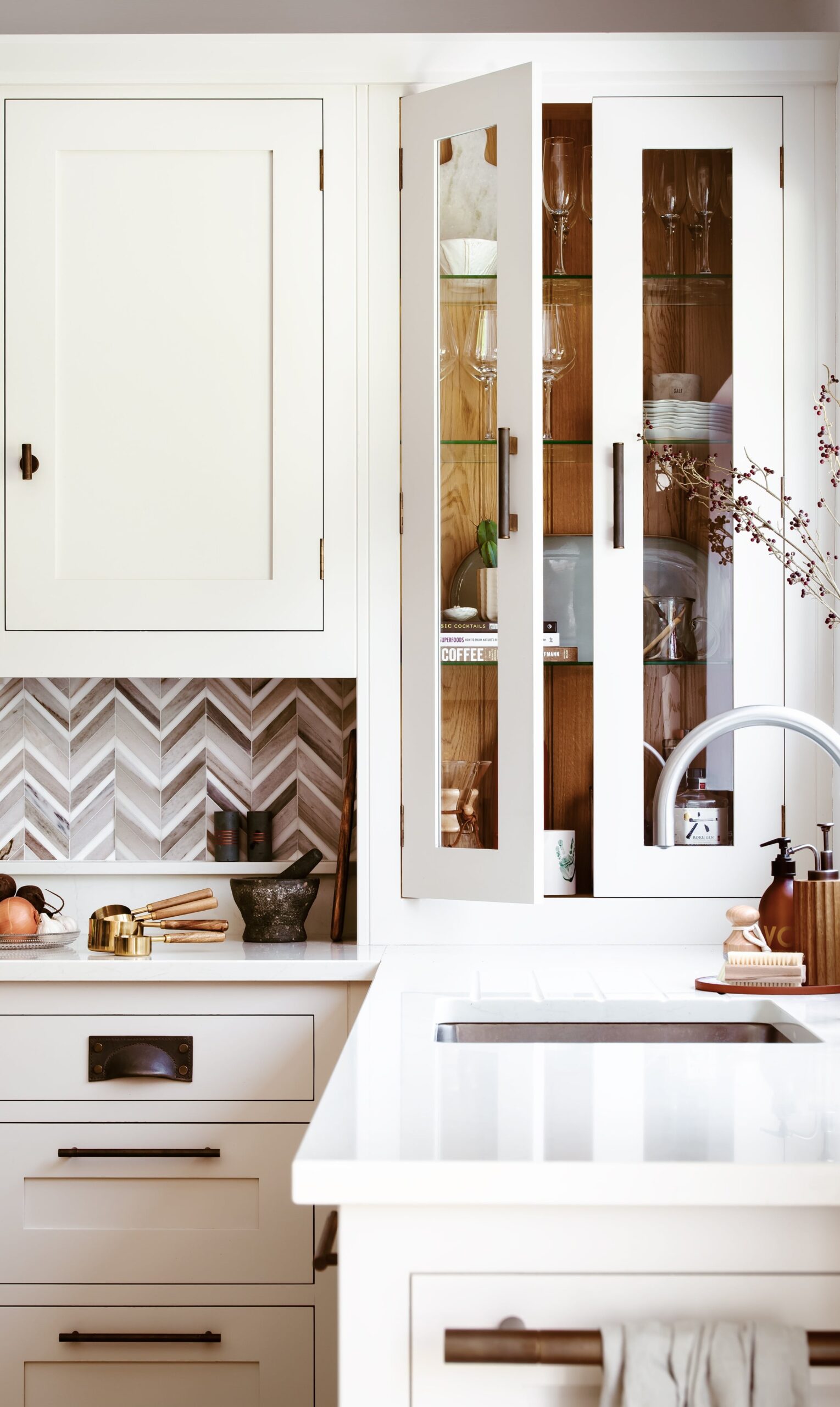 White kitchen cabinetry with white worktops and herringbone tiled splashback