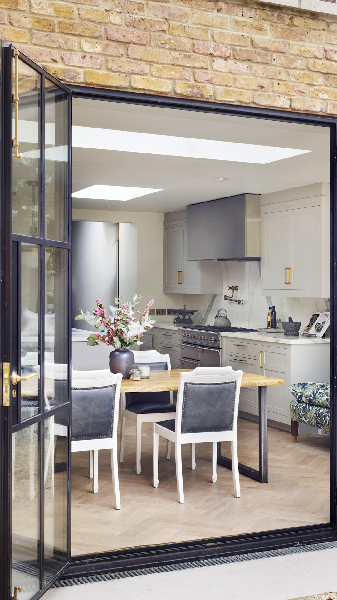 White kitchen design seen from a black framed glass door