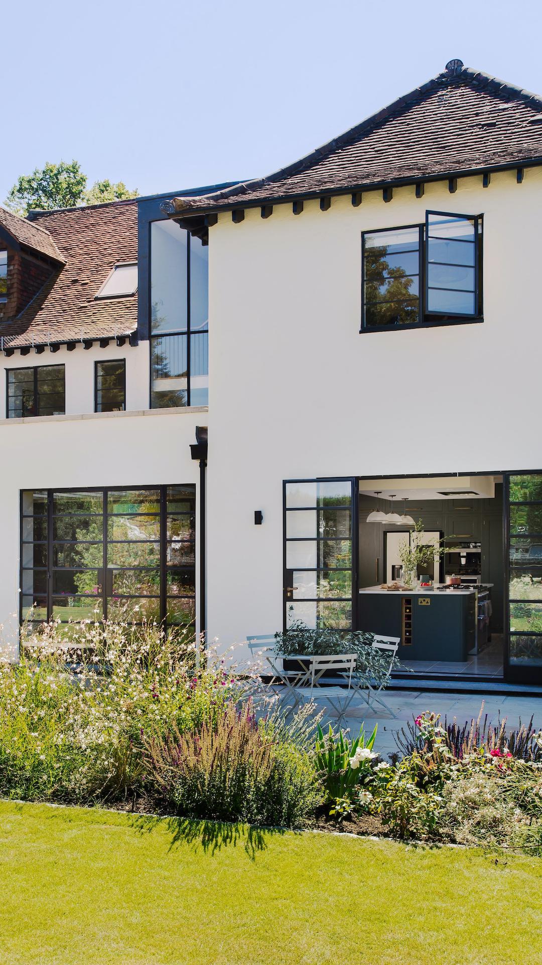 External view of Harvey Jones kitchen seen through large black framed glass sliding doors