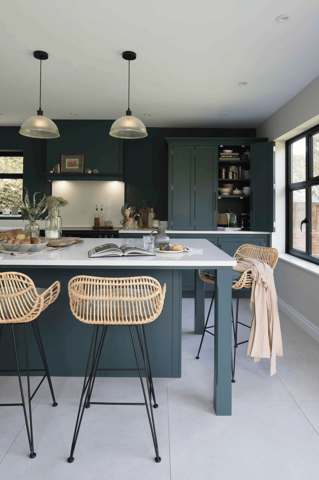 Teal kitchen island with white worktop and weaved back bar stools
