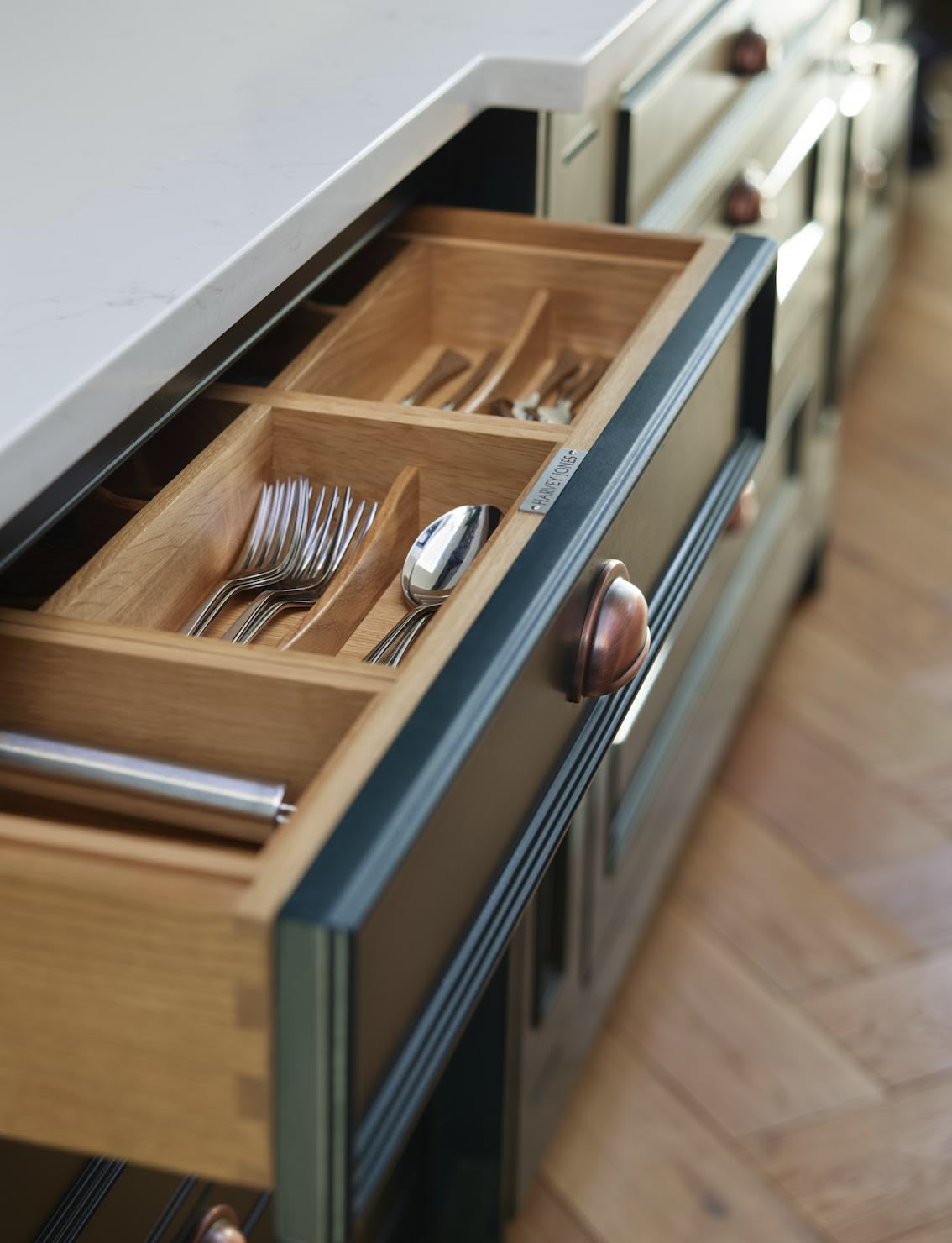 Green kitchen drawer open to show oak cutlery dividers